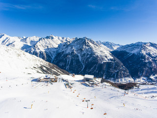 Fototapeta na wymiar Aerial view of ski resort in the Alps with ski lift and people skiing on the slope