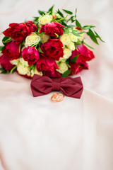 Close up of wedding bouquet of red tulips and white roses, wedding rings and butterfly bouquet to match. Place for text
