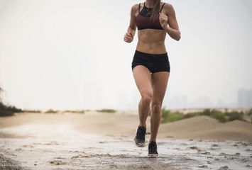 Strong athletic woman wearing black short tights and sports top showing six pack running with a desert background 