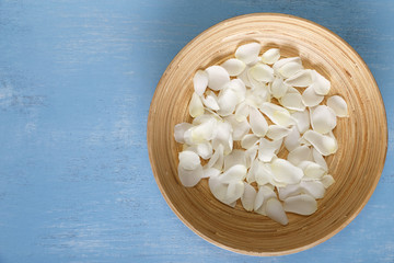 Petals of white roses on blue painted rustic background. Fresh natural flowers in bowl. Dirty grunge wooden board.