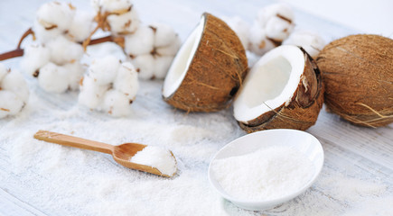 Still life with coconut, coconut flakes and white cotton flowers, healthy organic food concept