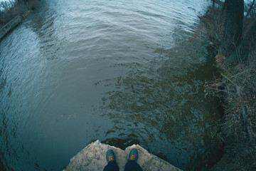 Legs on the edge of a concrete dam near the river