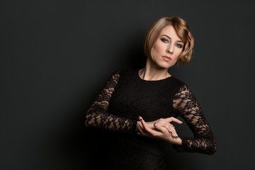 classical portrait of elegant blonde woman with a wave hairstyle and makeup on dark background