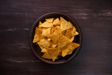 Nachos chips. Delicious salty tortilla snack on rustic plate. On wooden table background.