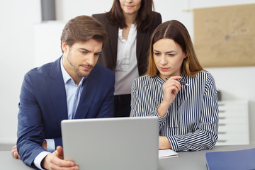 team im büro schaut konzentriert auf ein notebook