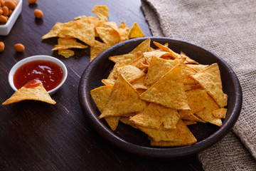 Nachos chips. Tortilla snack with sweet salsa or chilli sauce. Mexican salsa nuts. Rustic plate on wooden background.