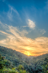 Fototapeta na wymiar Mountain forest landscape under evening sky with clouds in sunlight. Majestic sunset in indian Himalaya mountains. HDR image.