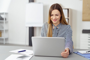 lächelnde junge mitarbeiterin im büro arbeitet am laptop