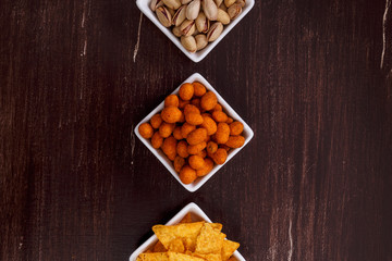 Nachos chips. Tortilla snacks. Mexican salsa and pistachios nuts. On rustic wooden background.