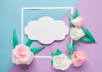 square frame with color paper flowers on the blue and violet background. Flat lay. Nature concept