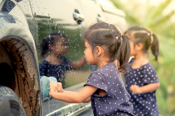 Cute asian little girl washing car in vintage color tone