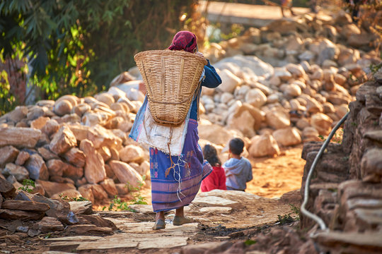 Nepalese woman carries huge wicker basket on her back at the street of Bandipur, Nepal