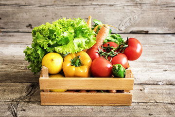 Vegetables in basket on wooden table - obrazy, fototapety, plakaty