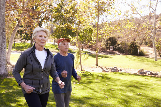 Side View Of Senior Couple Power Walking Through Park