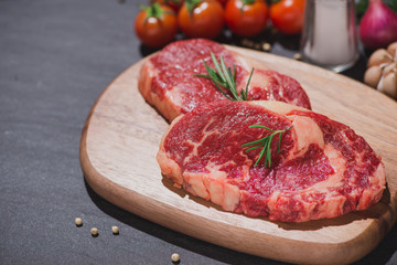 Fototapeta premium Raw beef on a cutting board with spices and ingredients for cooking.