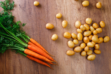 Potatoes with carrot. Raw new potato. Fresh natural vegetables. Organic food on wooden background.