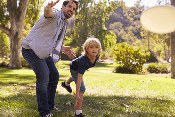 Father Teaching Son To Throw Frisbee In Park