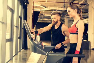 Fototapeta na wymiar Personal trainer instructing sporty woman on treadmill in gym