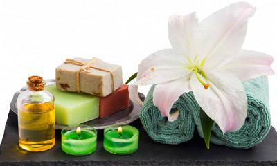 Spa setting with organic products, burning candles, towels and lily flower