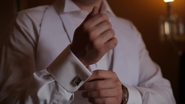 Groom is holding hands on the tie, wedding suit. close up of a hand man how wears white shirt and cufflink. Business man fixing black tie on white shirt. Groom on wedding day fixing tie, vintage