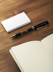 The business cards and notepad with the pen on a table from above.
