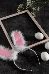 Easter bunny ears in a frame for pictures and eggs on a black background. Side view and space for text