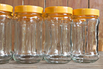 Glass jars with orange lids isolated on wooden.