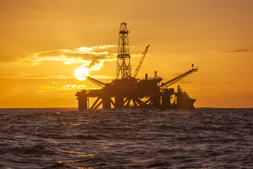 Fototapeta na wymiar Offshore Jack Up Rig in The Middle of The Sea at Sunset Time 