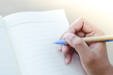 Hands with pen writing on notebook on nature light background