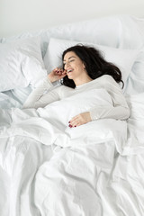 attractive woman in white sleepwear awakening in bed at home