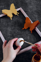 Workspace with easter decoration. Woman paints Easter eggs, slide view. Selective focus