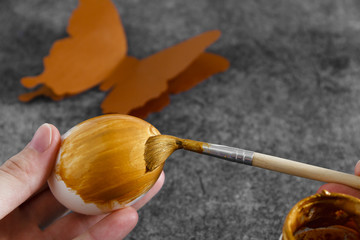 Workspace with easter decoration. Woman paints Easter eggs, slide view. Selective focus