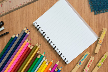 Blank notebook ,colorful pensils and Stapler on wooden desk for any idea on desk work.