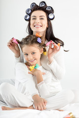 Fototapeta na wymiar Beautiful happy mother and daughter in curlers having fun together