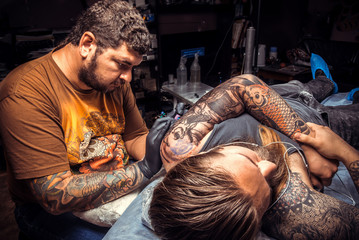 Obraz premium Tattoo artist makes tattoo in studio
