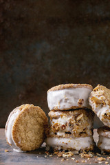 Set of homemade ice cream sandwiches in oat cookies with almond sugar crumbs over dark metal texture background. Close up