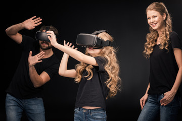 Happy family in black t-shirts having fun in virtual reality headsets