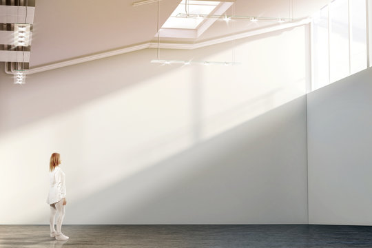 Woman walking near blank white wall mockup in modern gallery