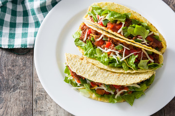 Traditional Mexican tacos with meat and vegetables on wooden background
