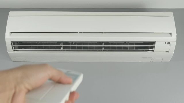 4k of hand holding remote control and turning on air conditioner at home