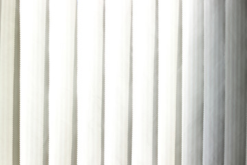 Vertical window blinds with sun light as a background