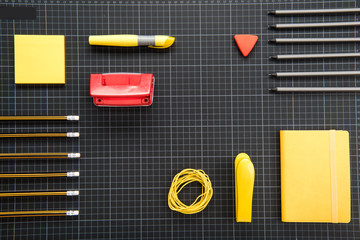 Top view of organized various office supplies on black background