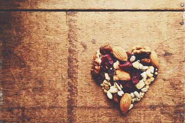Heart shaped granola with wholegrain cereals, nuts and raisins on wooden background