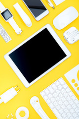 Flat lay of office supplies, keyboard, digital tablet, smartwatch and smartphone on yellow