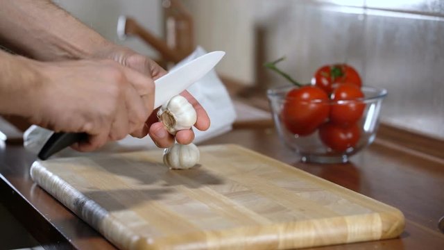man peels garlic for cooking bruschetta