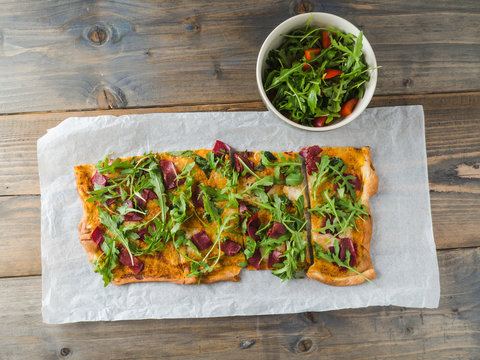 Tasty appetizing pizza with meat, rugula and a salad
