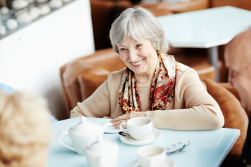 Waist-up portrait of pretty senior woman with wide smile having good time with her best friends...