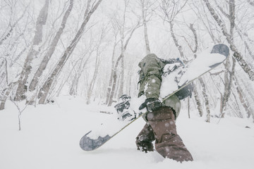 Snowboarder walking in winter forest