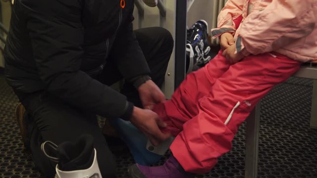 A father helping his daughter to put on her ski boots, 4K