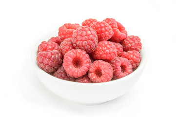 Raspberry fruits at white ceramic cup isolated on background